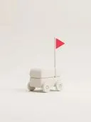 Minimalistischer weißer Spielzeugwagen auf Rädern mit einer kleinen roten dreieckigen Flagge
